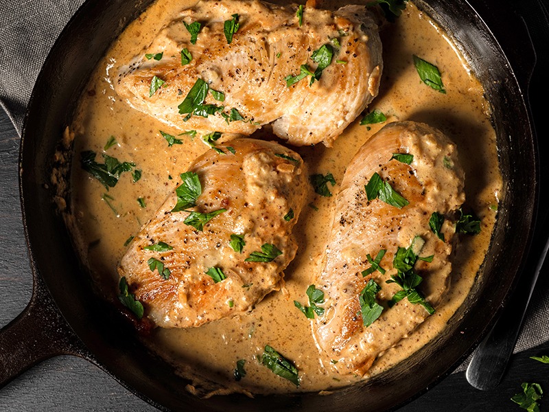 Boneless chicken breasts covered with a mix of Deli Dijon Mustard and Original Stone Ground Mustard and cooking in a skillet.