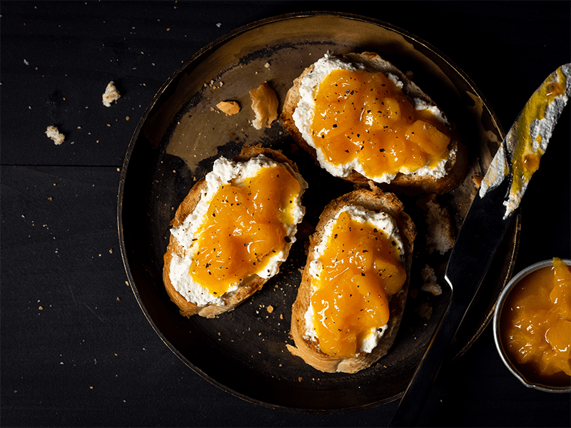 Slices of toast on a plate topped with ricotta and mustard apricot jam